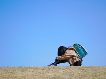 土手でうつむく子の画像