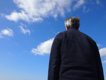 男性の後ろ姿と空の画像